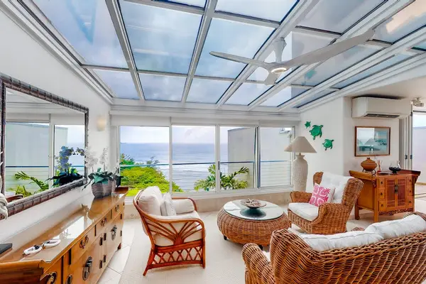 Enclosed living space offers wicker seating, dining, and tropical scenery