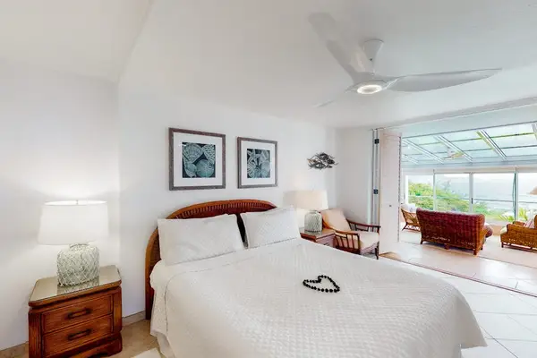Cozy bedroom showcases comfortable linens, decorative accents, and ocean glimpses