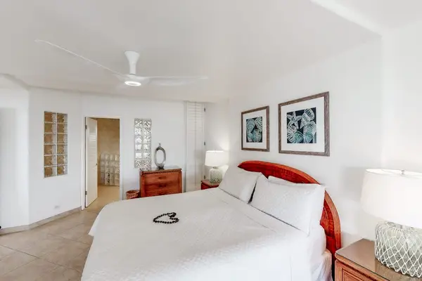 Stylish bedroom offers restful bedding, bedside tables, and framed artwork