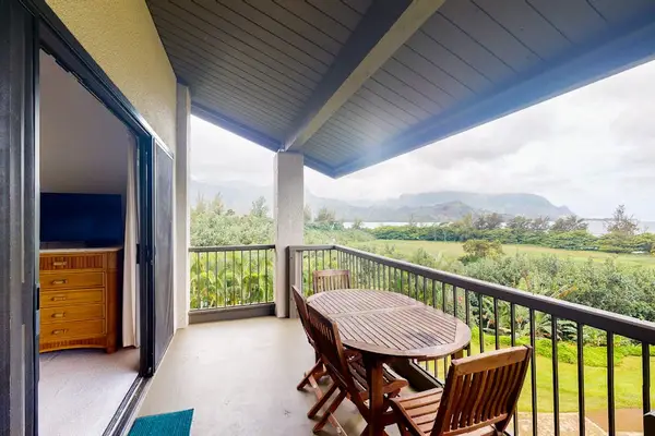Covered balcony dining overlooks mountains gardens and bright blue island