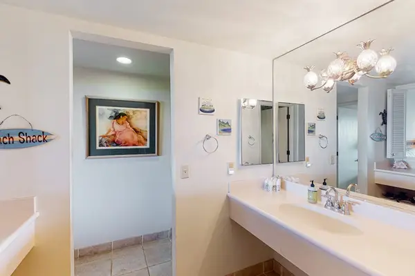 Bathroom vanity features mirror lighting polished fixtures and spacious counters