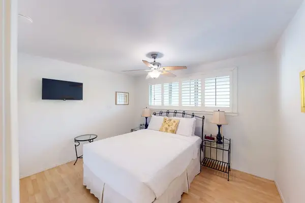 Bedroom features a comfortable bed ceiling fan and bright island light