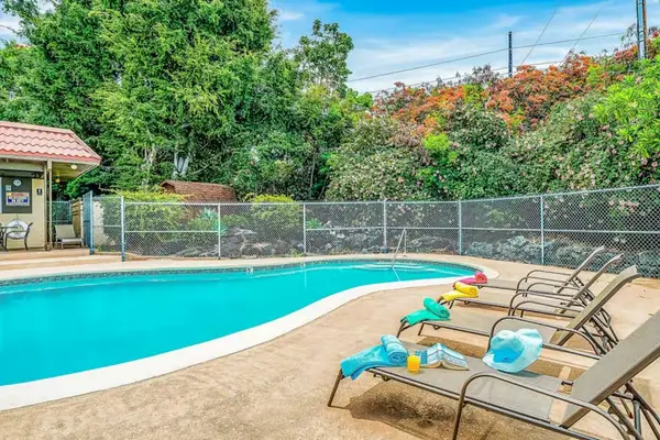 Poolside Lounge Area with Sunbeds, Swimming Pool, and Lush Garden Backdrop