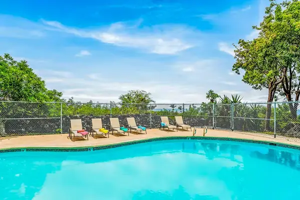 Sunny Swimming Pool Area with Lounge Chairs and Scenic Views