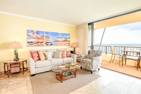 This bright living room features a relaxing ocean view from a private balcony and comfortable furniture.