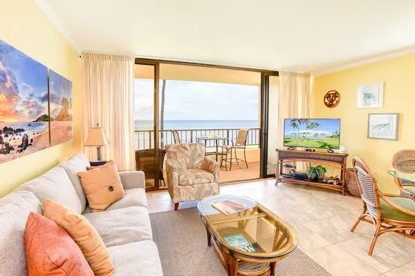 This bright living room features a relaxing ocean view from a private balcony and comfortable furniture.