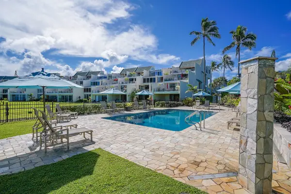 Property entrance with a shared pool, surrounded by tropical palm trees