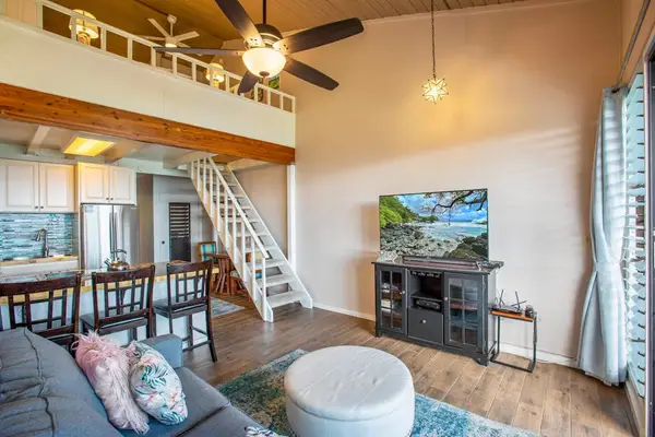 Living room with flat screen tv, sleeper sofa and rays of light streaming in from the lanai.