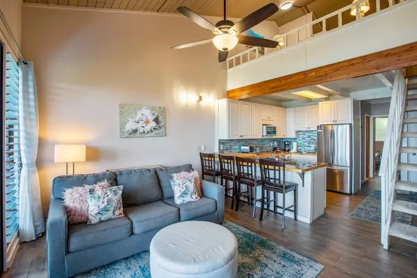 Living room with flat screen tv, sleeper sofa and rays of light streaming in from the lanai.