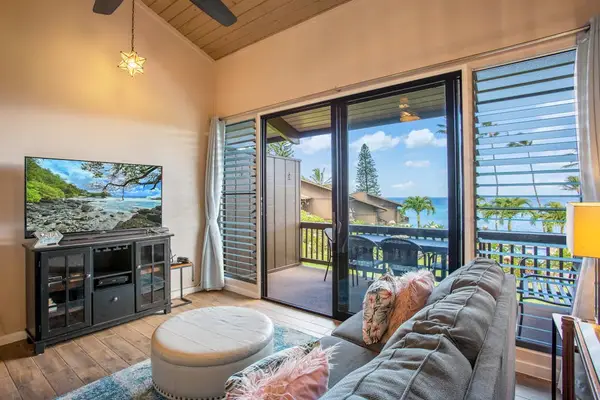 Living room with flat screen tv, sleeper sofa and rays of light streaming in from the lanai.