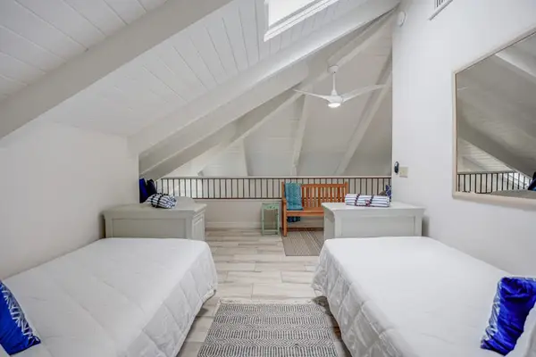 Cozy loft bedroom with two twin beds and vaulted ceilings.