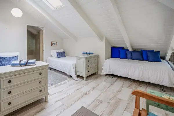 Bright loft bedroom featuring twin beds and vaulted ceilings.
