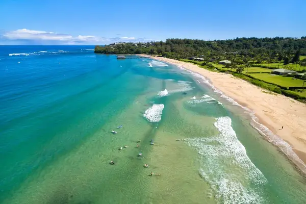 Aerial beach view captures sandy shores, turquoise water, and waves