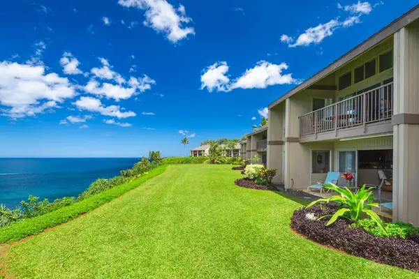 Coastal property exterior features manicured lawns, gardens, and ocean views
