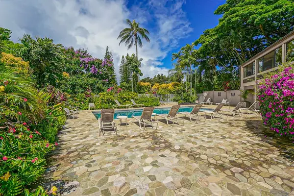 Poolside setting features seating, tropical greenery, and open skies