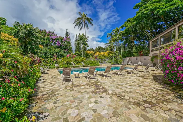 Poolside retreat features comfortable loungers, vibrant landscaping, and open skies