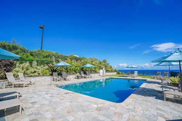 Pool deck showcases clear water, lounge chairs, and tropical landscaping