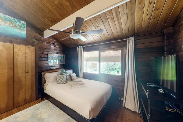 King bedroom with ceiling fan and flat screen tv.