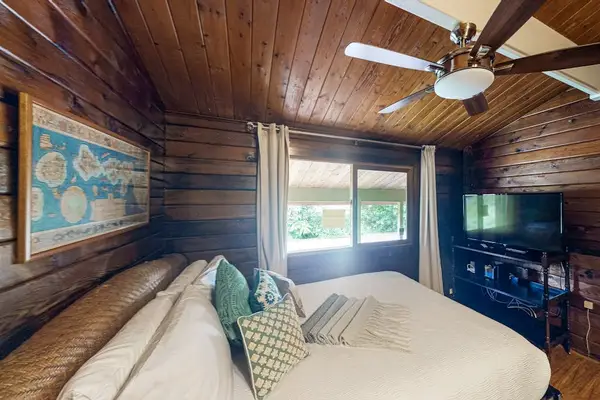 King bedroom with ceiling fan and flat screen tv.