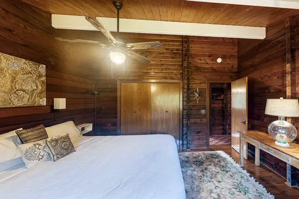 Guest bedroom with a queen bed, ceiling fan and lots of natural light.