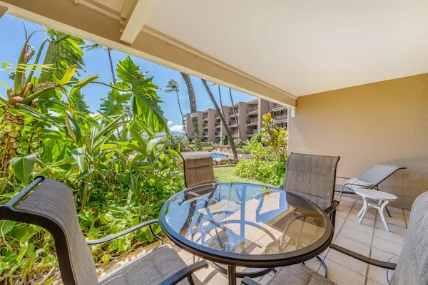 Covered lanai surrounded by tropical greenery, perfect for outdoor dining.