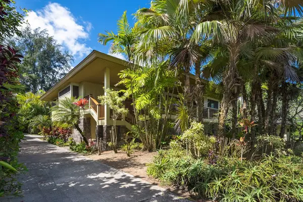 Garden pathway leads through lush landscaping toward the tropical residence