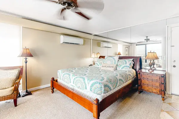 Spacious bedroom with natural lighting and a large mirrored wall