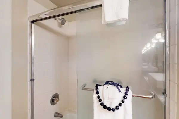 Glass shower features towel storage, grab bar, and clean tilework
