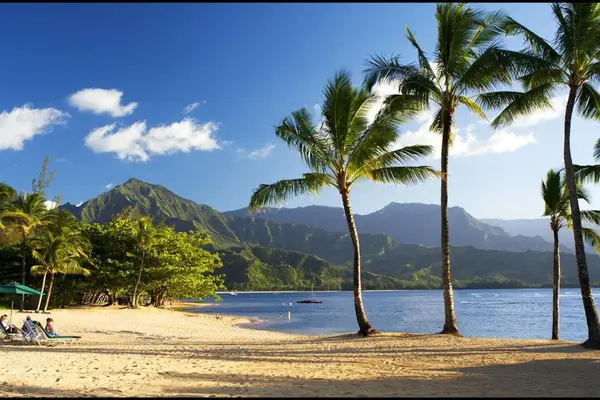 Sandy beach features swaying palms, mountain views, and peaceful waters