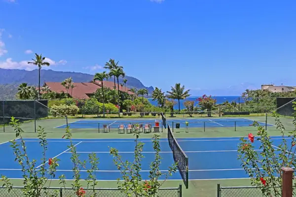 Sunlit tennis courts overlook palms mountains and resort rooftops nearby