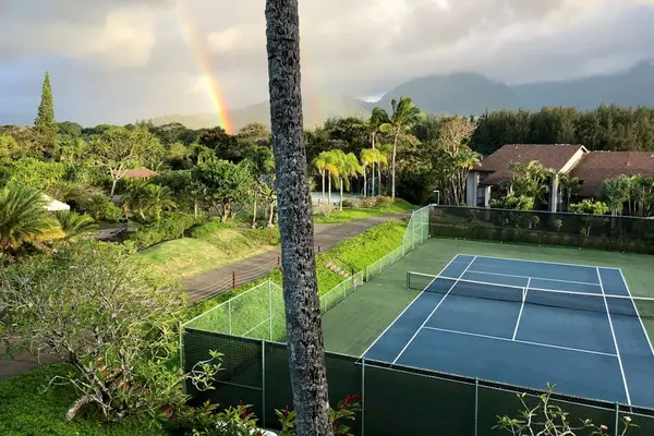 Palm framed tennis court welcomes sunset play amid mountain scenery
