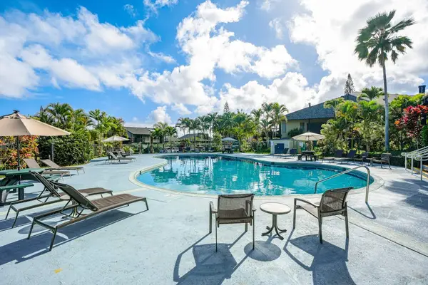Poolside chairs invite afternoon reading beneath palms and drifting clouds