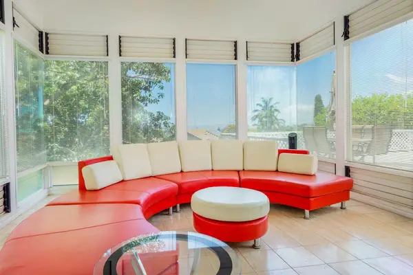Sunlit lounge features curved seating, windows, artwork, and tropical greenery