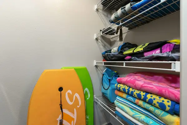 Walk-in closet stores beach gear towels and colorful boogie boards
