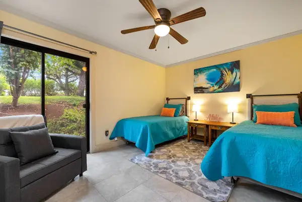 Second bedroom features two single beds tropical artwork and windows