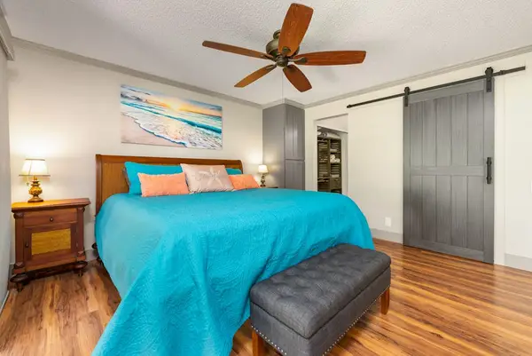 First bedroom showcases colorful bedding warm floors and ceiling fan