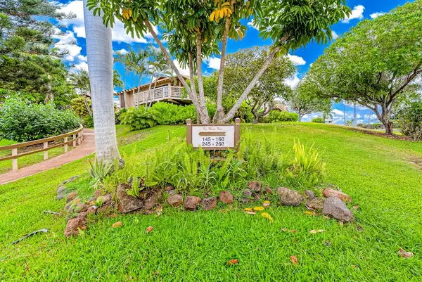 Landscaped property entrance features lush grass tropical plants and signage