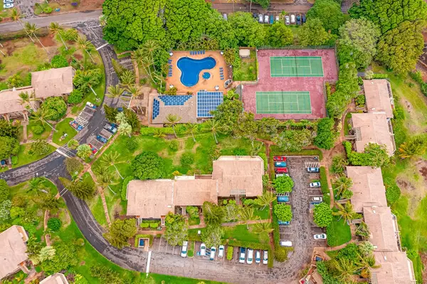 Aerial view highlights resort pool tennis courts and tropical surroundings