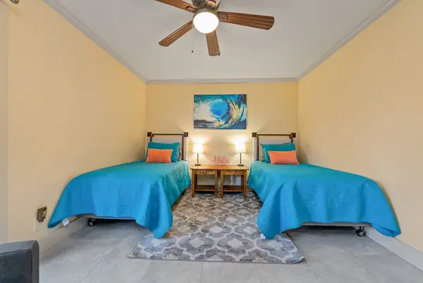 Second bedroom offers two single beds and bright tropical decor