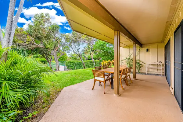 Shaded exterior walkway provides seating beside lush tropical landscaping outdoors