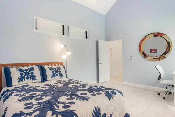 Bedroom features bed, bedding, artwork, windows, lamps, fan, and lighting