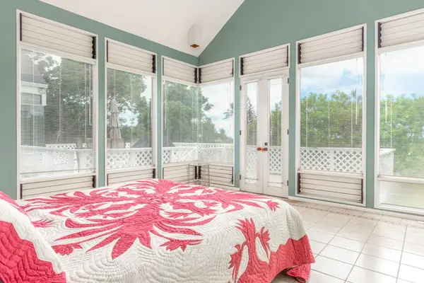 Bedroom features bedding, windows, palms, artwork, daylight, ceiling fan