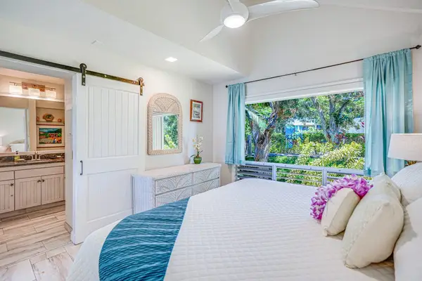 Bright primary bedroom with tropical décor and natural light.