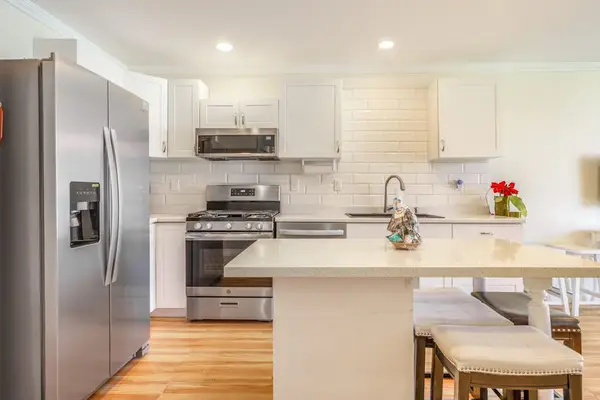 Bright Kitchen Island with Stool Seating and Stainless Steel Appliances