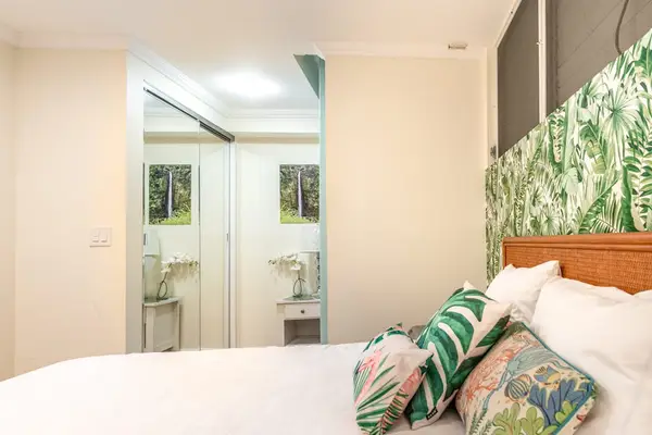 Bedroom View Featuring Mirrored Sliding Closet Doors and Leaf-Pattern Accent Wall