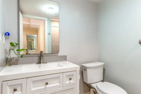 Clean Bathroom Vanity with White Cabinetry, Large Mirror, and Toilet