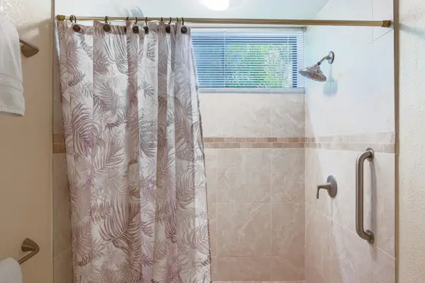 Tiled Walk-In Shower with Safety Grab Bar & Tropical Accent Curtain