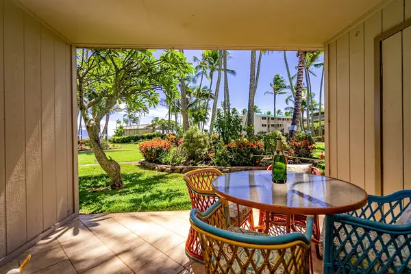 Covered patio dining space overlooks lush gardens and tropical landscaping