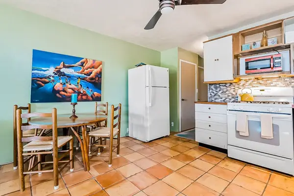 Dining area features colorful artwork, kitchen appliances, and comfortable seating
