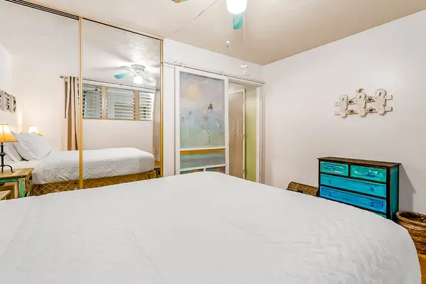 First bedroom includes queen bed, mirrored wardrobe, dresser, and windows